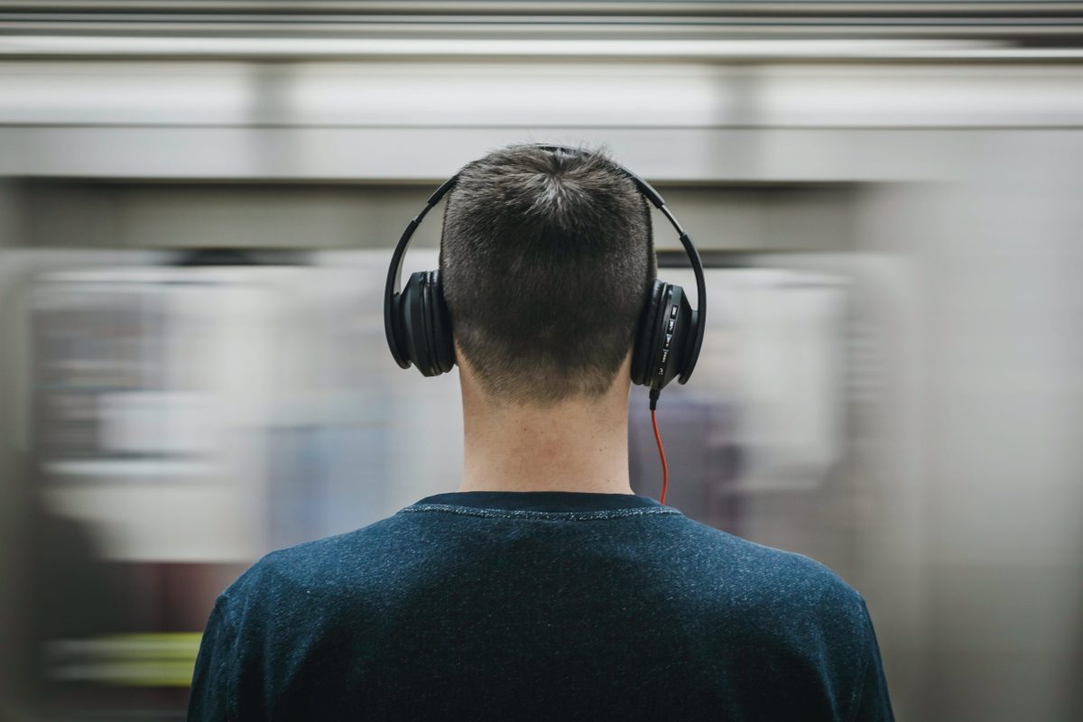jakob-owens-WUmb_eBrpjs-unsplash A man standing in the subway with a pair of headphones on